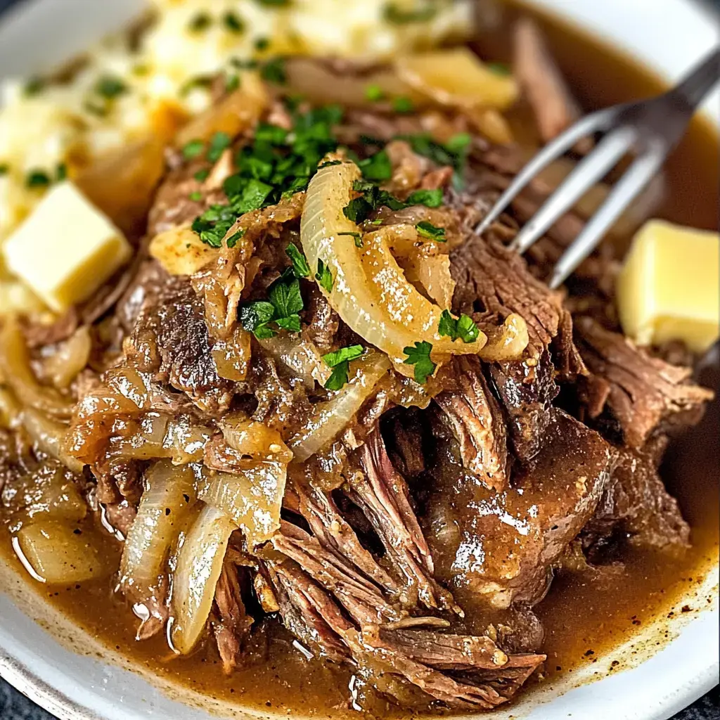 Zoom sur du bœuf effiloché avec oignons et herbes, accompagné de purée et beurre sur assiette blanche.