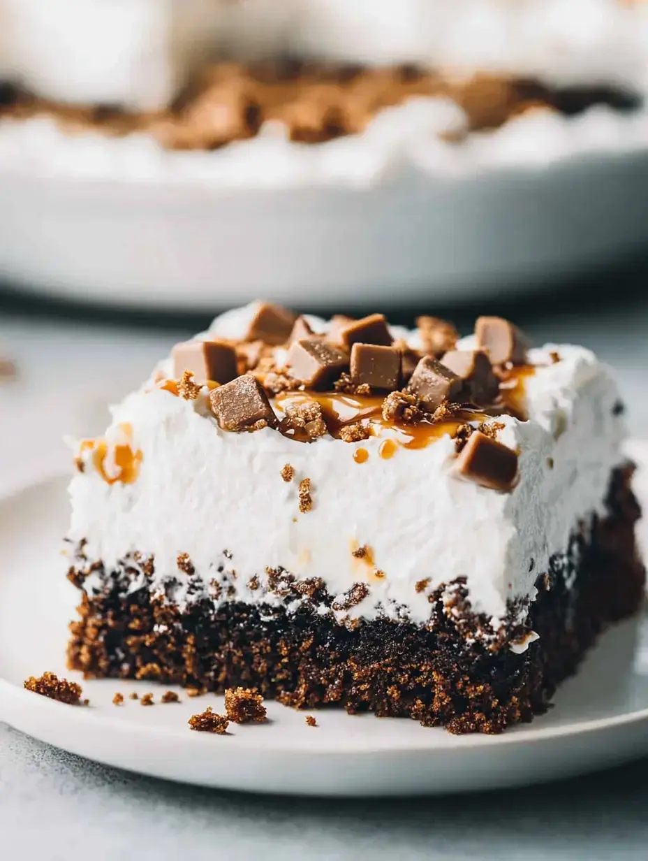 Une part de dessert avec des couches de gâteau au chocolat, crème fouettée, filet de caramel et morceaux de chocolat sur le dessus.