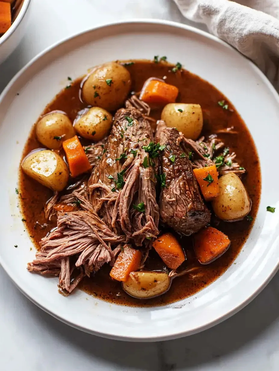 Une assiette de bœuf tendre effiloché entouré de pommes de terre nouvelles, de carottes et de bouillon, garnie de persil haché.
