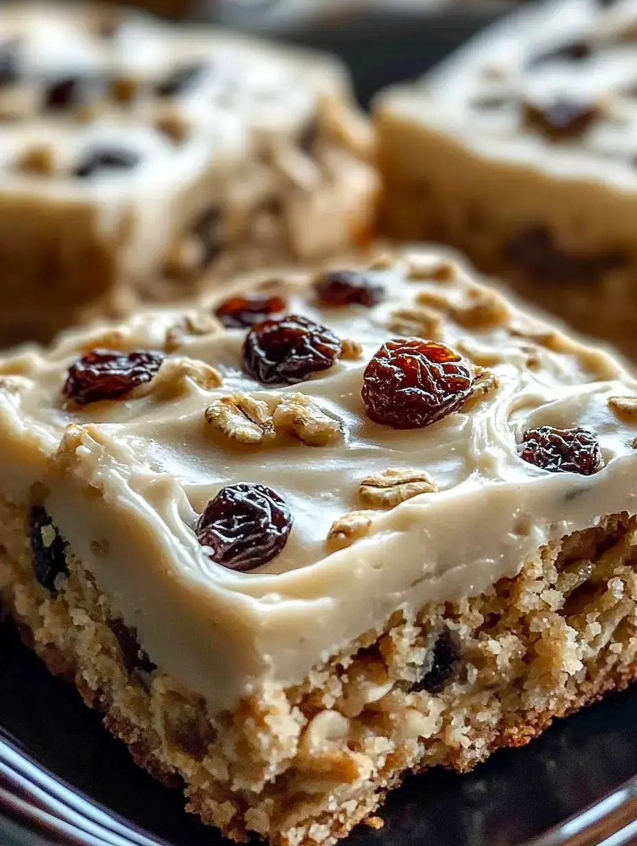 Une vue rapprochée d'une tranche de dessert garnie de glaçage crémeux, de raisins secs et de flocons d'avoine sur une assiette sombre.