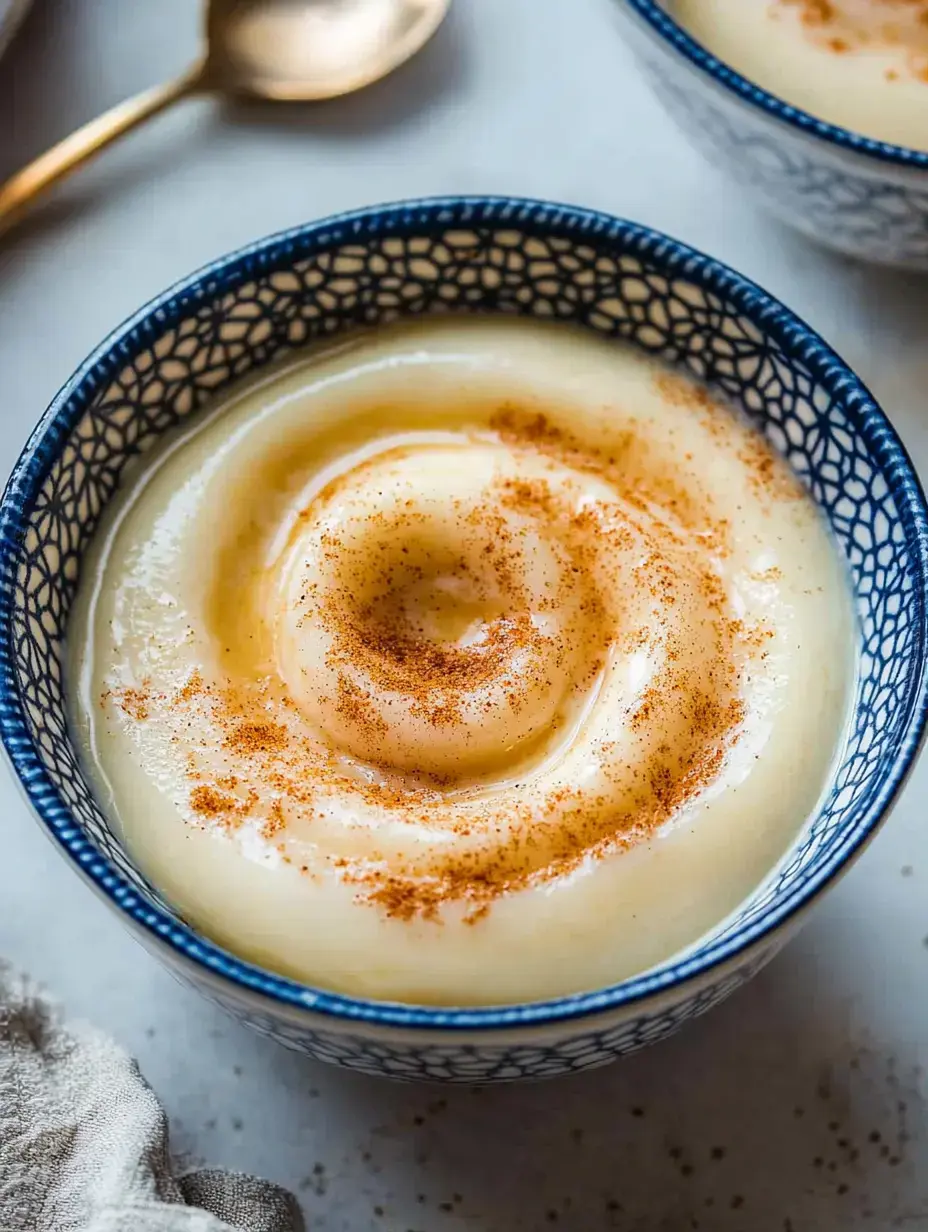 Un dessert crémeux surmonté d'un tourbillon de cannelle dans un bol bleu à motifs.