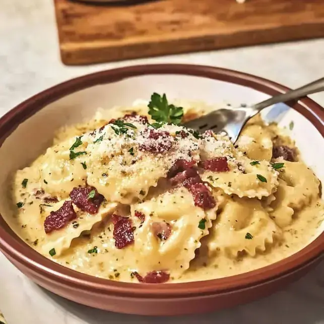 Un bol de pâtes crémeuses garni de lardons croustillants, de fromage râpé et de persil frais.
