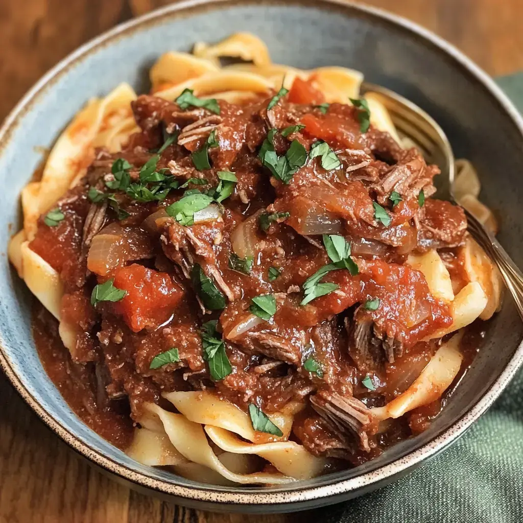 Un bol de pâtes nappé d’une sauce bœuf tomate riche, parsemé de persil frais.
